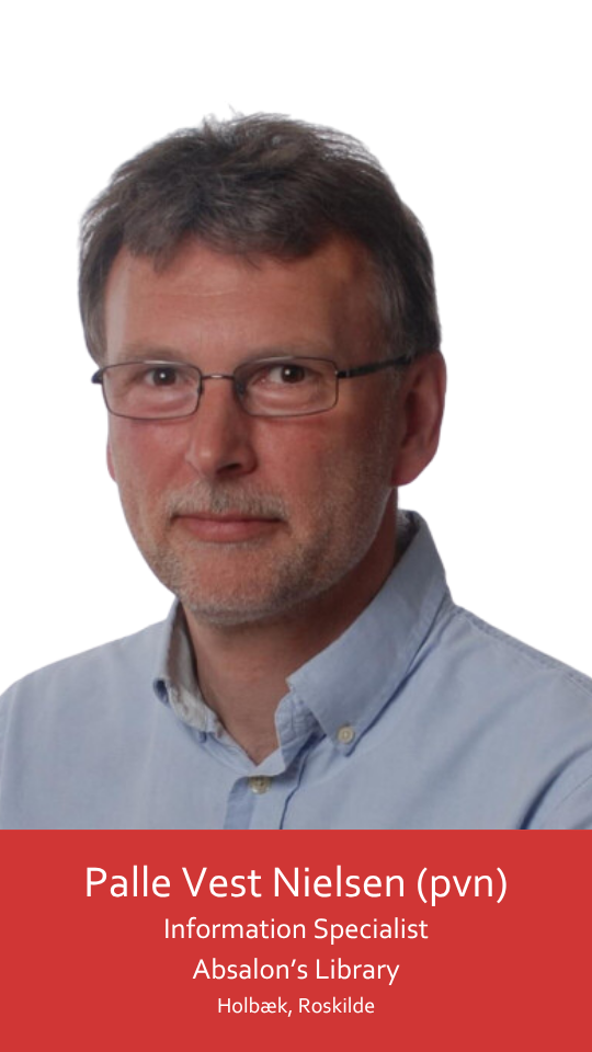 This image shows a middle-aged man wearing black glasses and a light blue shirt. He looks directly at the camera with a content expression and a slight smile. His hair is short, dark, and streaked with gray-brown. His chin is slightly raised as he looks into the camera lens, giving him a confident appearance.