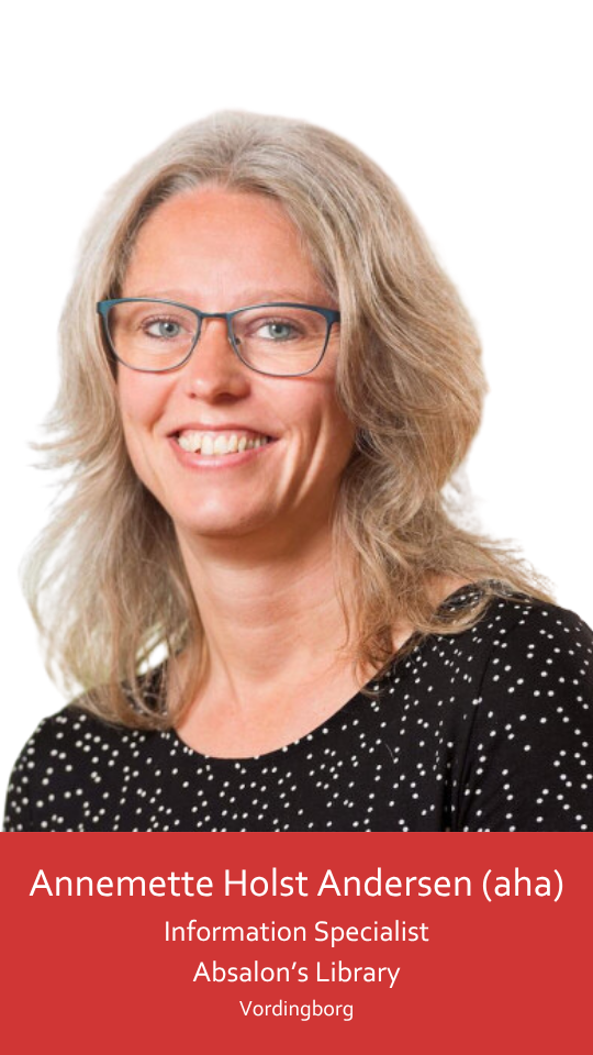 The image shows a woman with shoulder-length gray hair, wearing petrol blue glasses and a black top with white polka dots. She has green eyes and smiles broadly, her eyes crinkling at the corners as she looks directly at the camera.